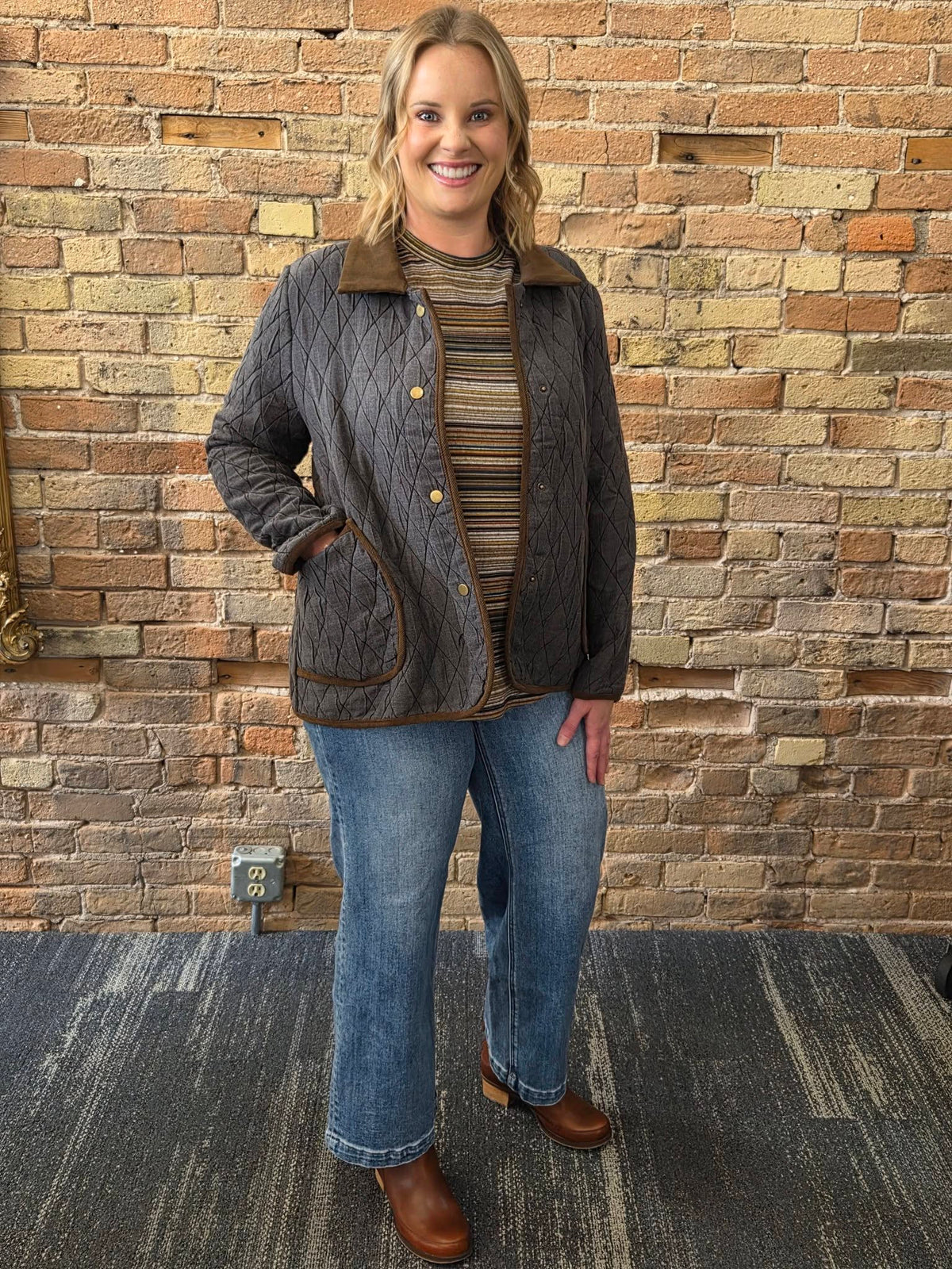 Model wearing dark quilted barn jacket with brown collar and trim
