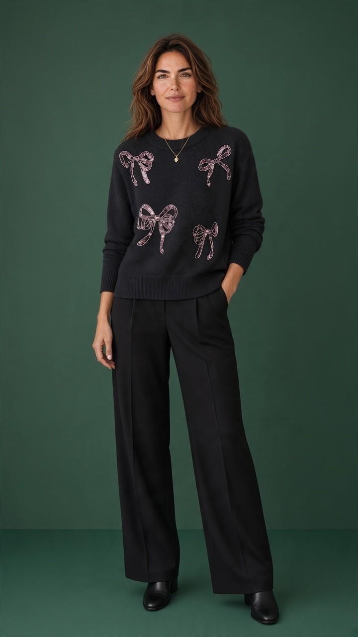 Black sweater with sequin bows styled with black wide-leg trousers.
