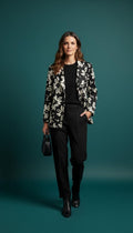 Black and white floral A-line jacket worn by a woman against a teal background