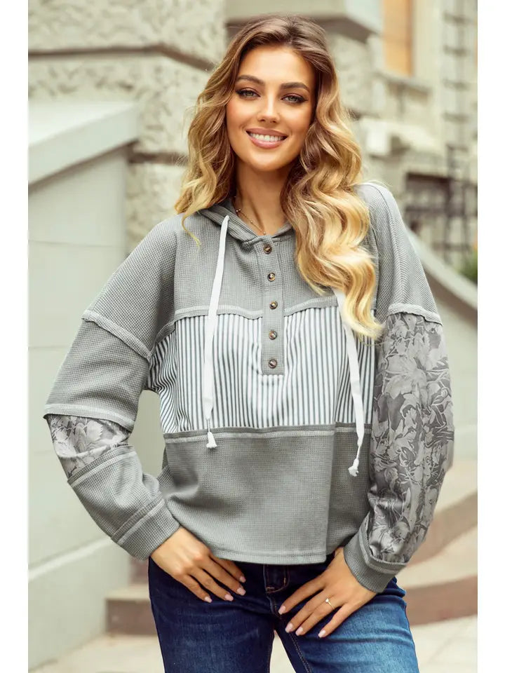 Gray waffle-knit hoodie with floral jacquard sleeve panels and striped button placket, front view