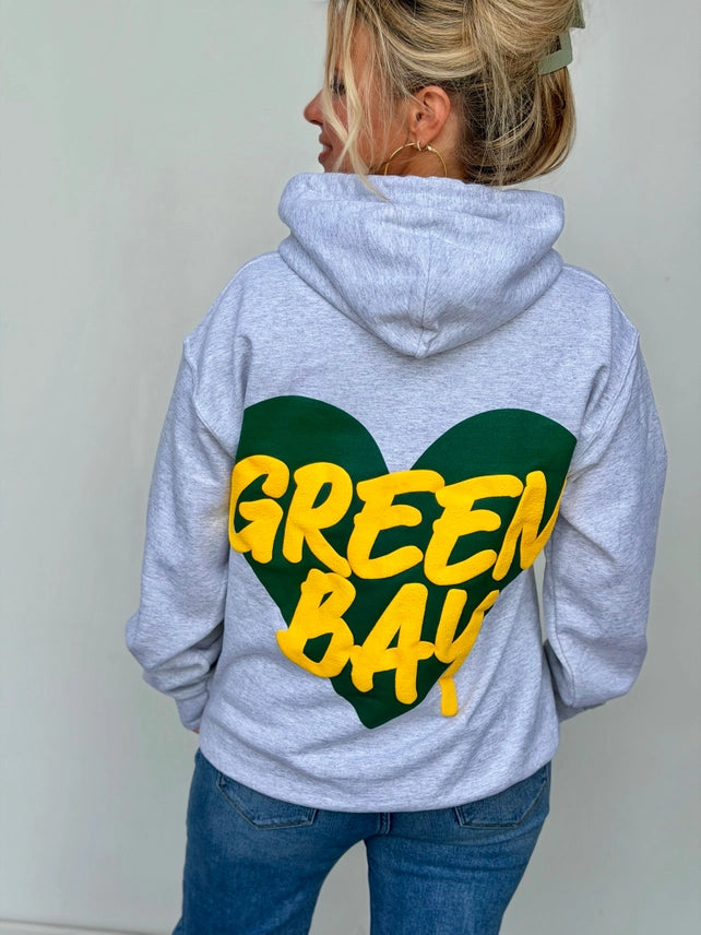 Back view of an ash gray hoodie with a large green and gold Green Bay heart puff print