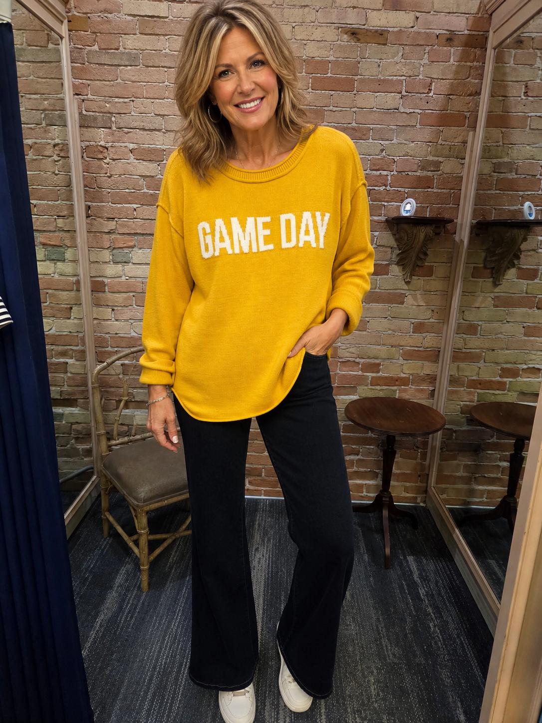 Model wearing gold Game Day sweater with black flare pants